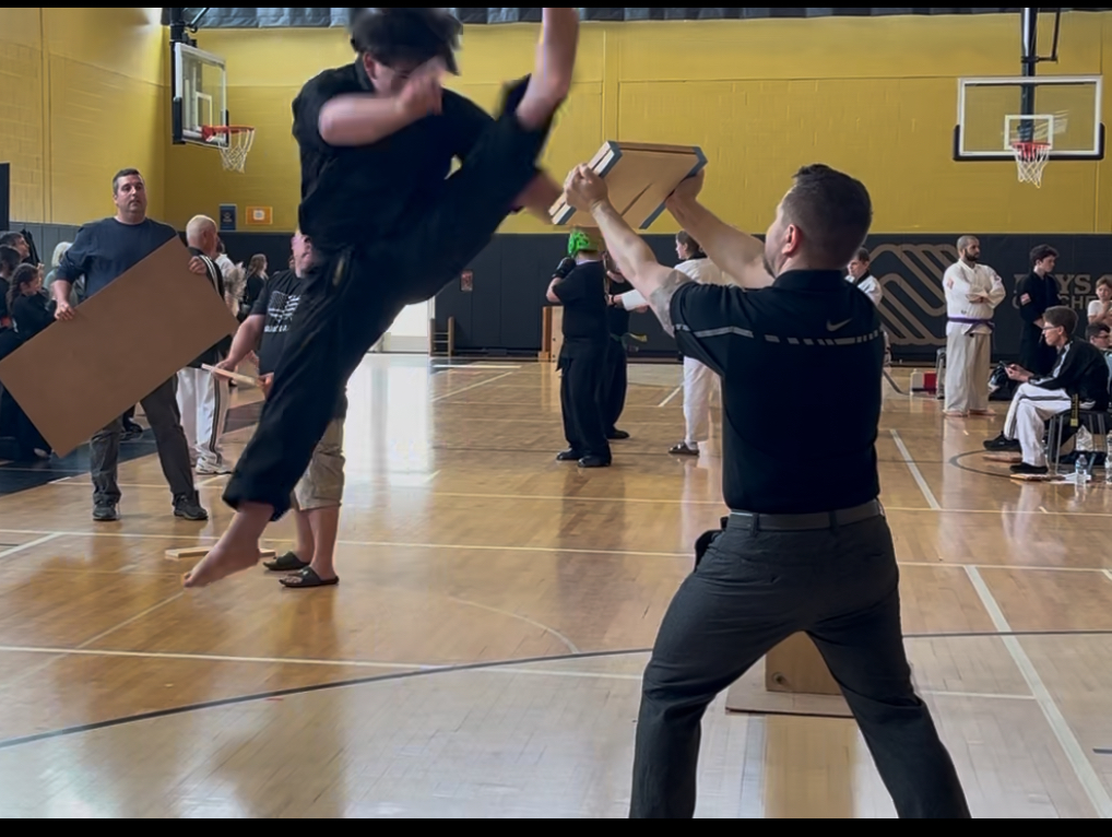 Black belt jump-kick board break at tournament